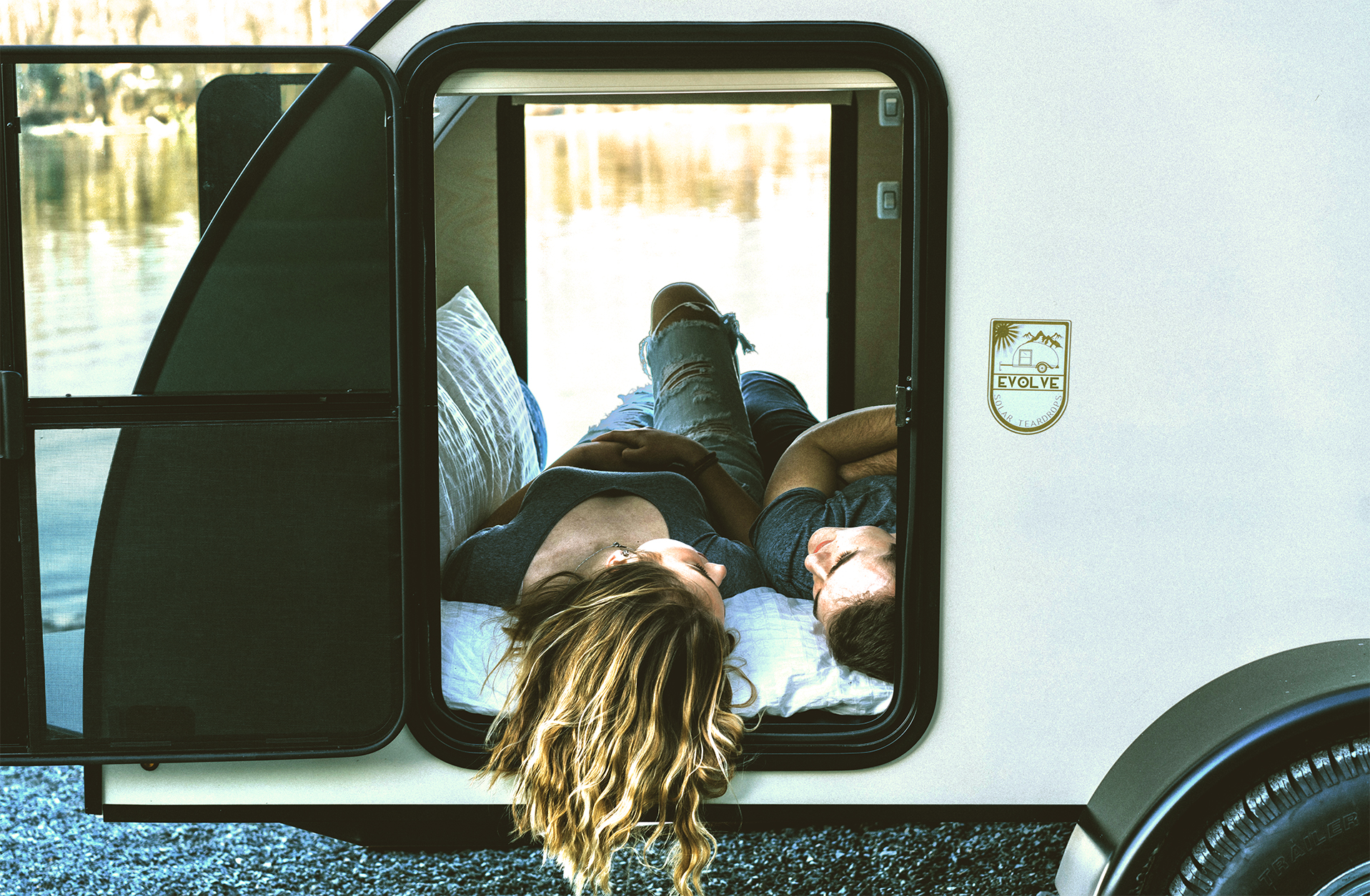 Woman and Man laying on the bed of the compact Evolve Solar Teardrop Trailer