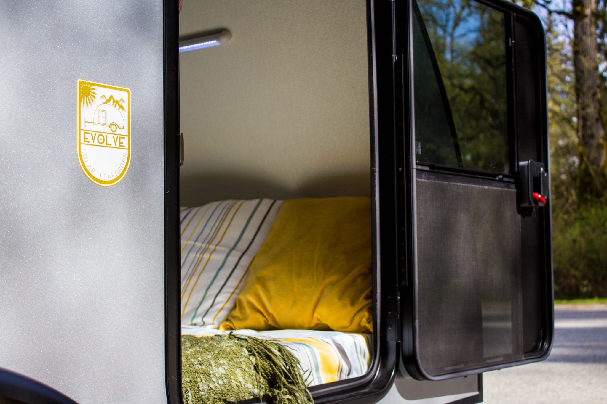 Side angle view of the door interior and bed on the Evolve Outing Teardrop Trailer