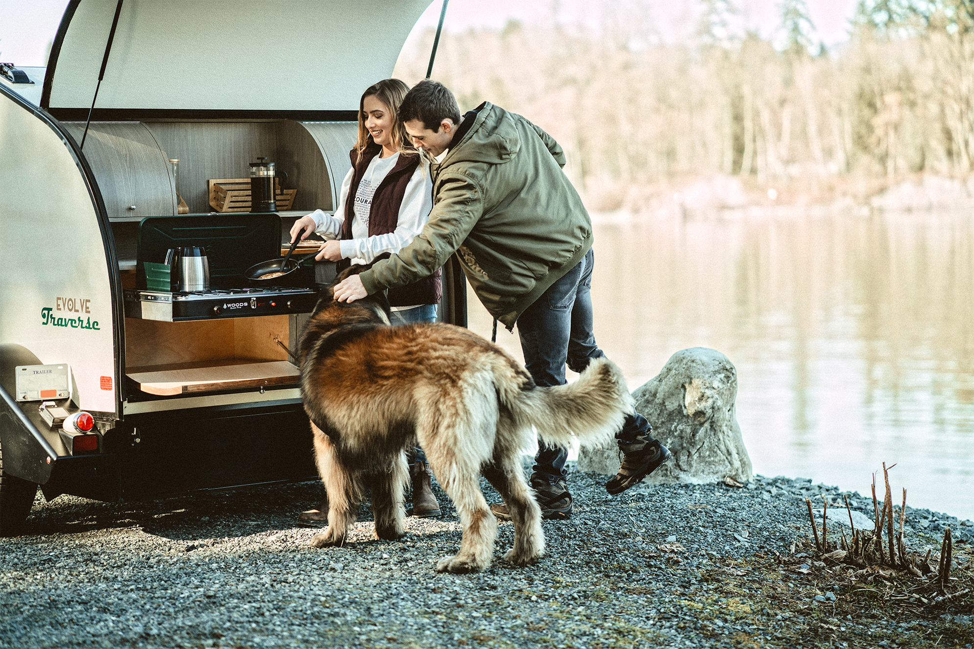 Man and woman with their dog cooking out of the Evolve Traverse Teardrop camping trailer